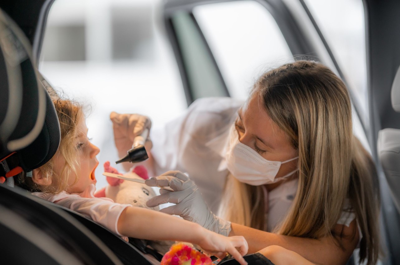 FNP-C, Dior Wood, examines a pediatric patient's throat for strep.