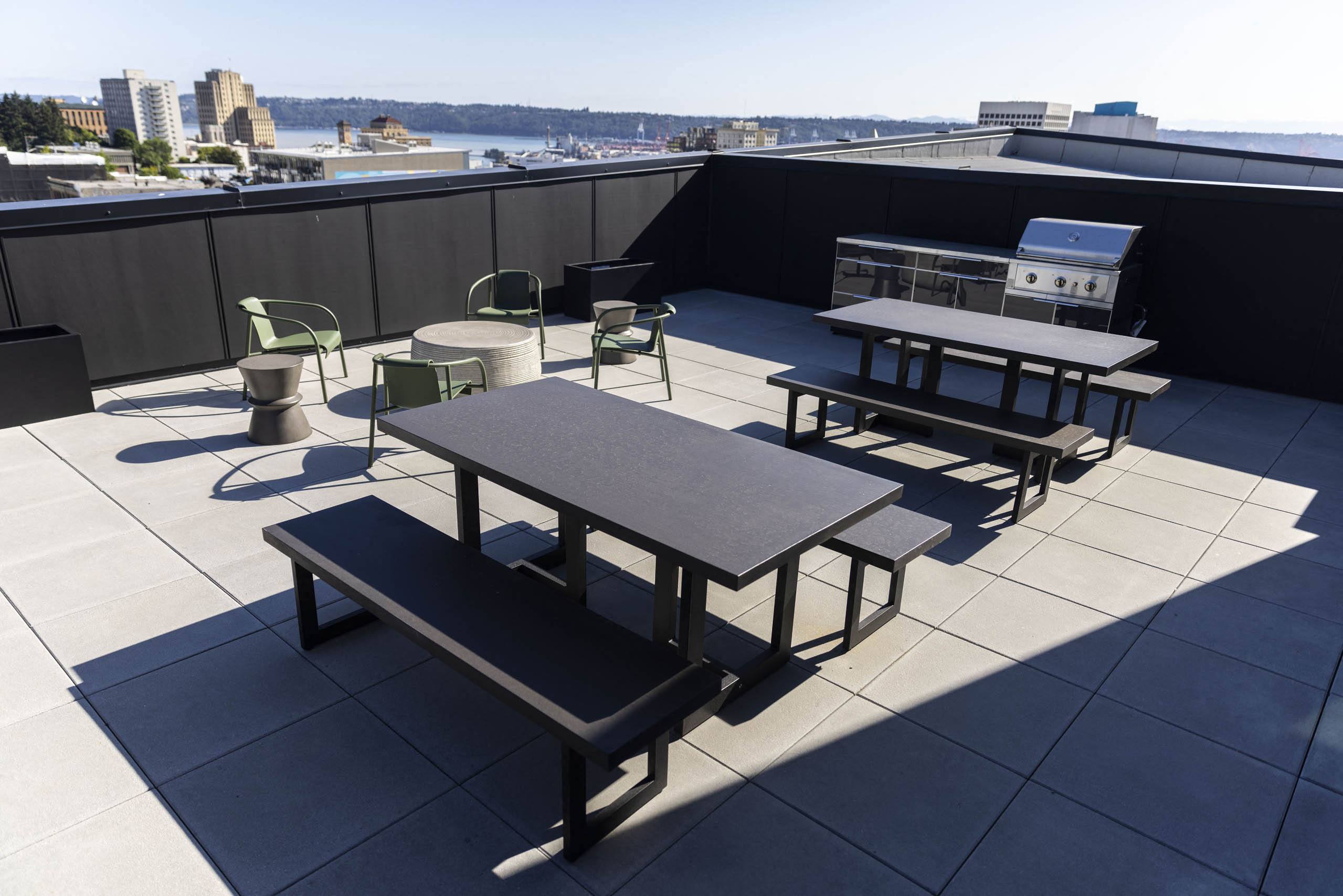 tables and chairs on the rooftop of a building with a city in the background