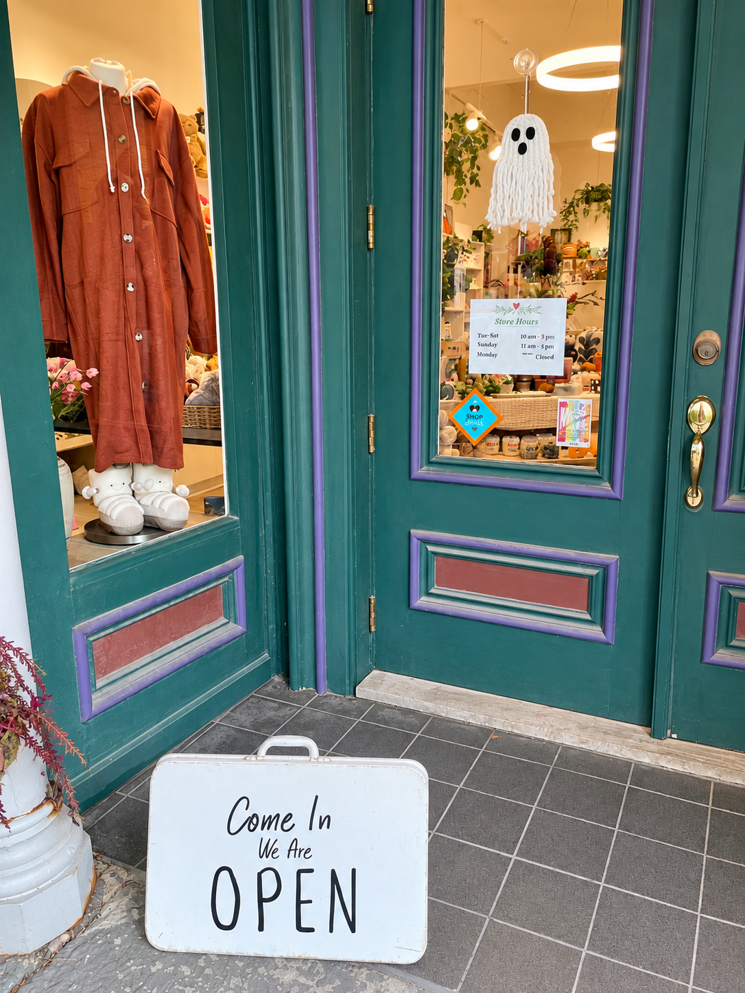Decorate’s welcoming entrance features a “Come In, We Are Open” sign, colorful green doors, a season 