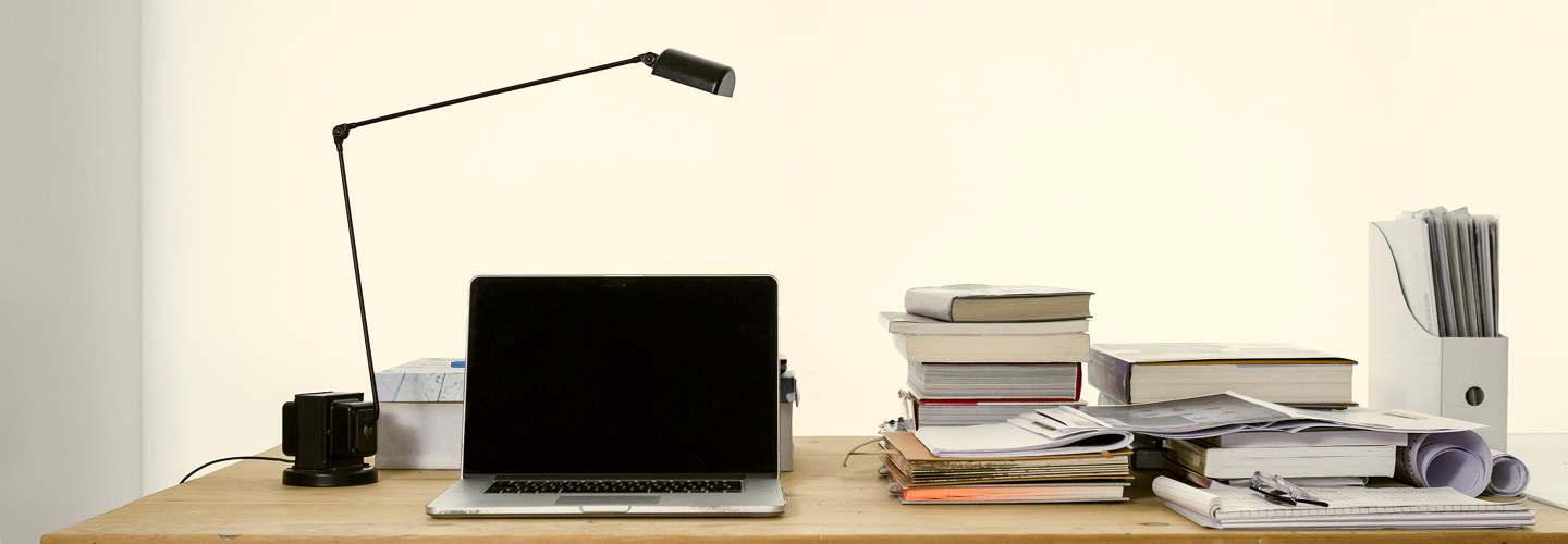 Office setup with a laptop and stacks of books.