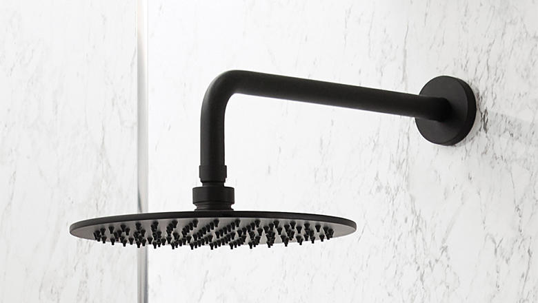 A black waterfall Bathstore shower head protrudes from a white tiled wall