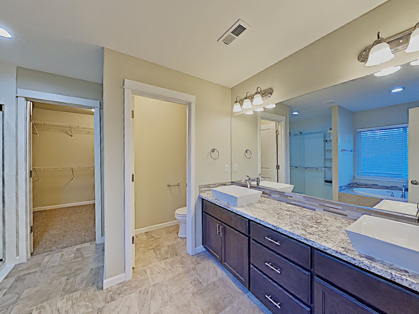 Luxurious bathroom with dual-sink vanity, large walk-in closet and stunning tile at Invitation Homes Seattle.