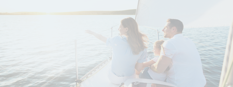 Young parents with their child on the bow of a sailboat enjoying the view.