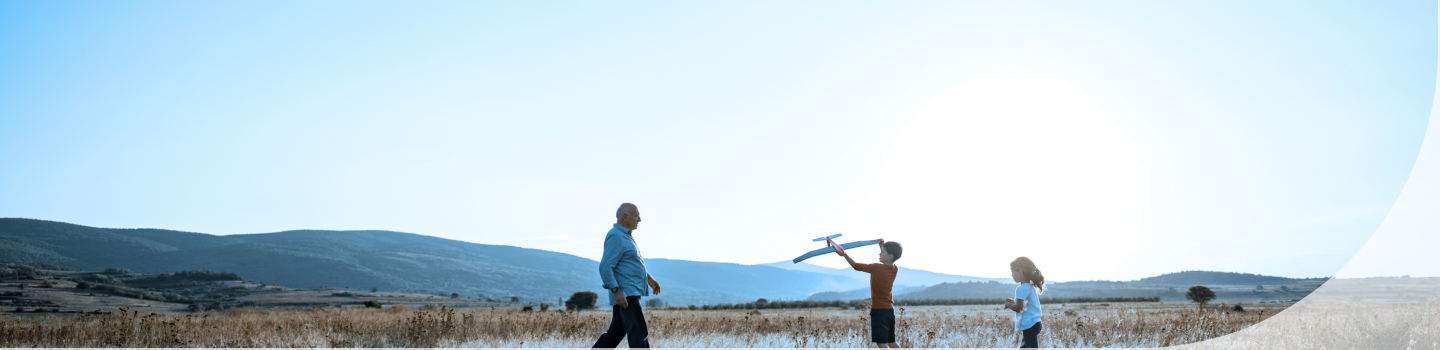 A grandfather and grandchildren playing outdoors.