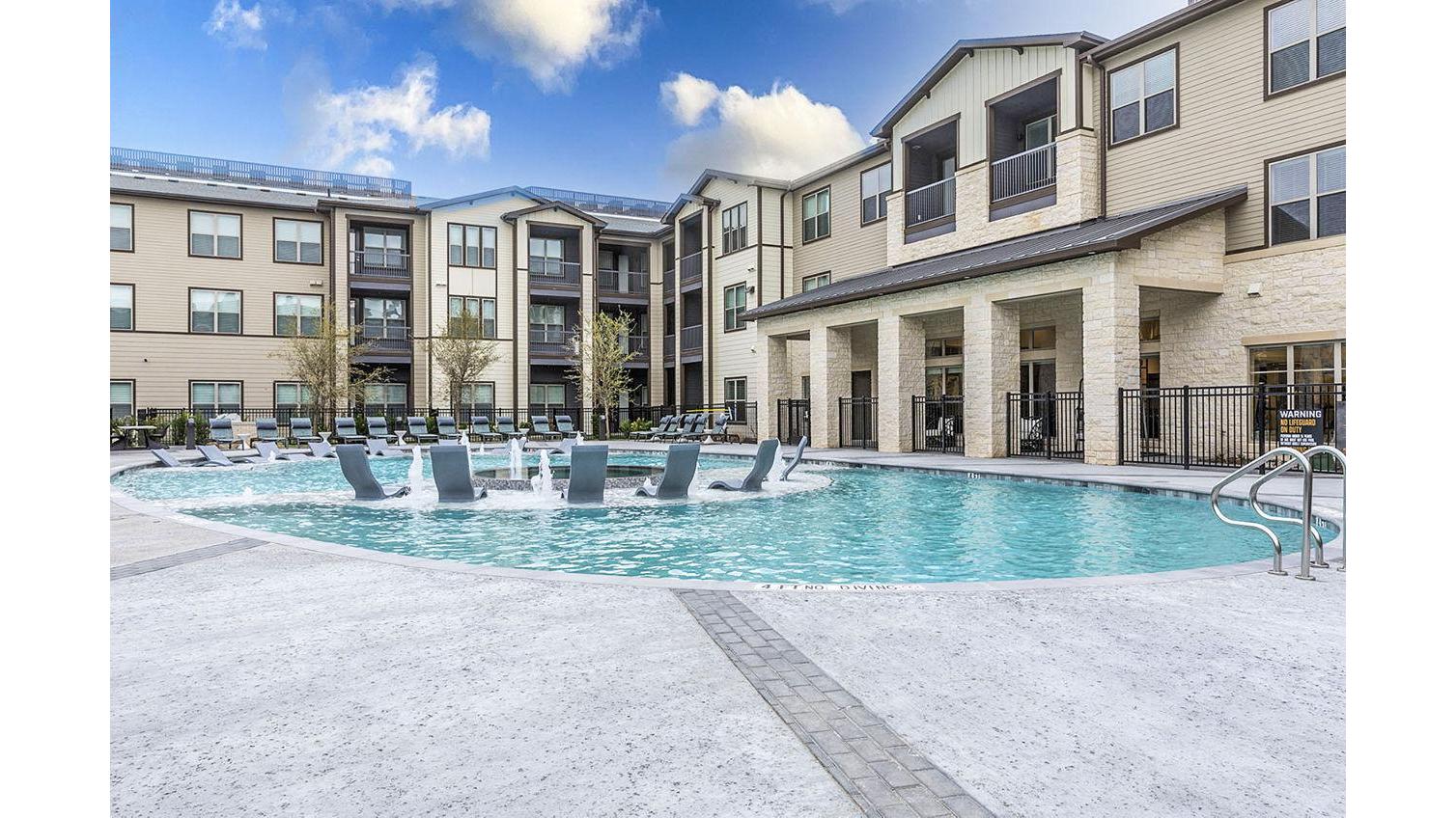 A swimming pool in front of apartment buildings. 