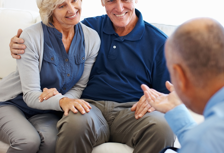 A man and woman on a couch speaking to their financial advisor.