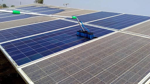 Specialized brush equipment cleaning a multi-panel solar array, illustrating professional maintenance designed for photovoltaic panel surfaces.