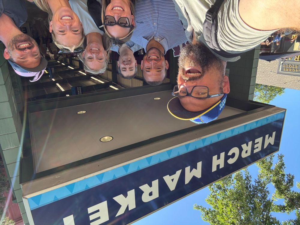 A cheerful group selfie of the Clarity Financial team gathering under the Merch Market overhang while exploring the fairgrounds.