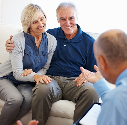 A man and woman on a couch speaking to their financial advisor.