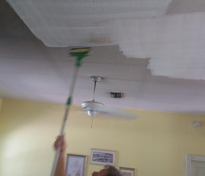 This picture shows the ceiling being prepped for future painting after a fire damage. Soot is wiped off using a special cleaning tool called a Chemical Sponge. This special sponge will remove fire soot without causing it to spread further.