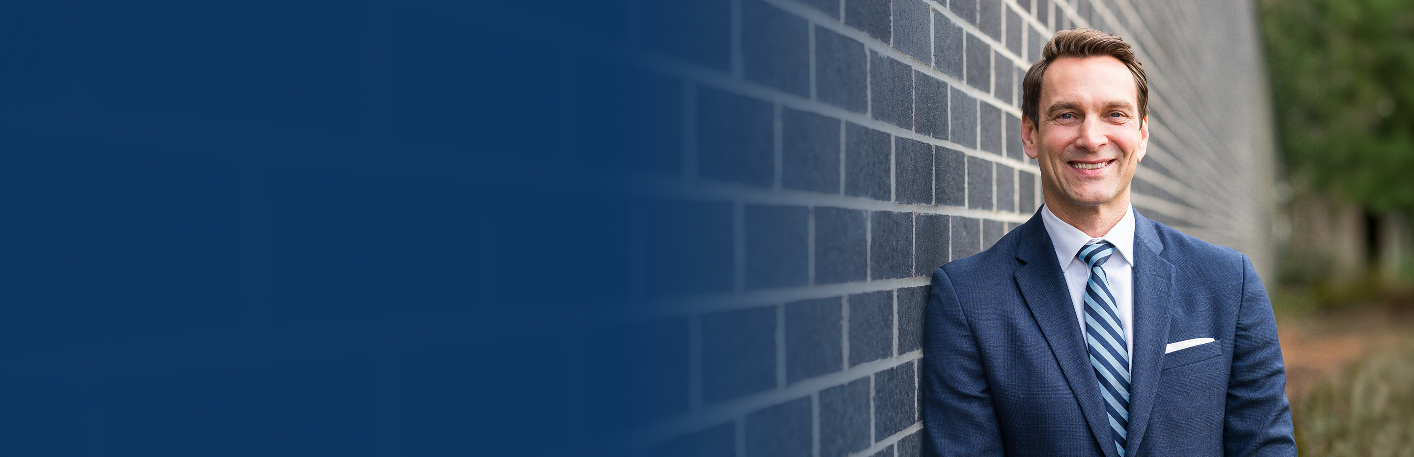 Ed Fairhurst casually leaning against a brick wall.