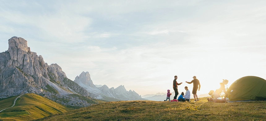 Two young families setting up camp together on the side of a mountain.