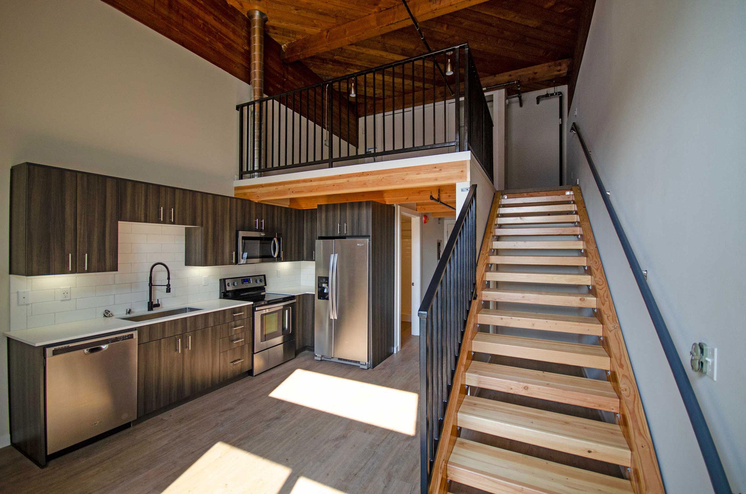 A modern kitchen with a staircase leading to the upper floor.
