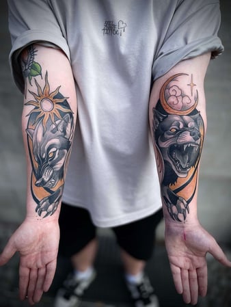Eisenherz Tattoo und Piercing Magdeburg - Symmetrische Unterarm Tattoos mit wolfartigen Wesen, Mond, Sonne und grafischen Flächen in gedeckten Farben. Starke Matching Tattoos für Keywords wie Wolf Tattoo, Unterarm Tattoo, Paar Tattoo, Fantasy Tattoo...