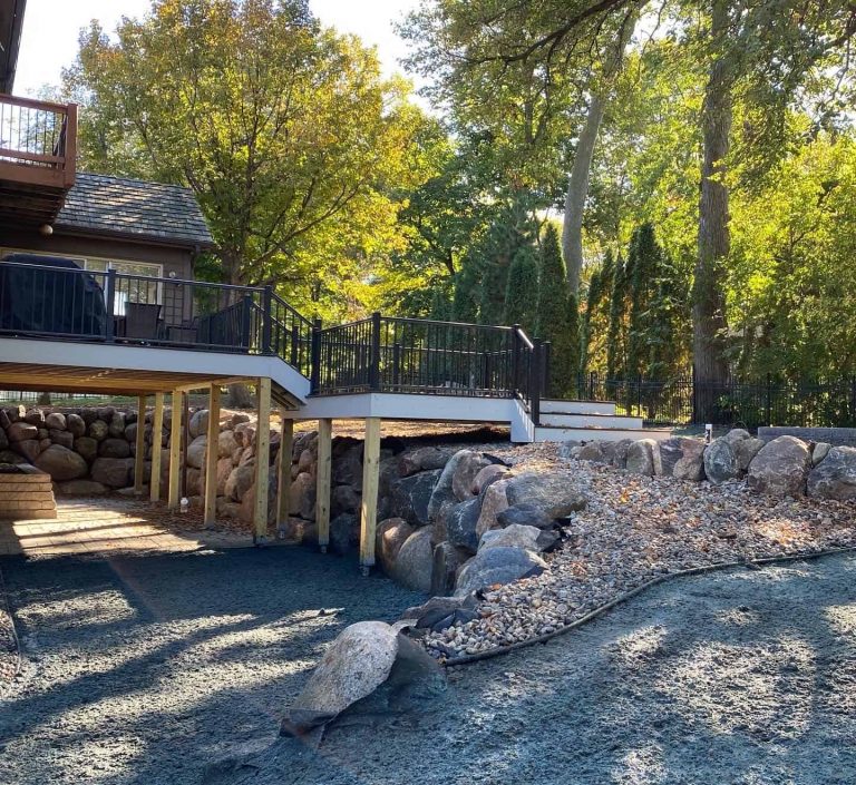 Natural boulders meet modern outdoor living. This retaining wall creates a stunning backdrop for a newly built deck and patio area.
