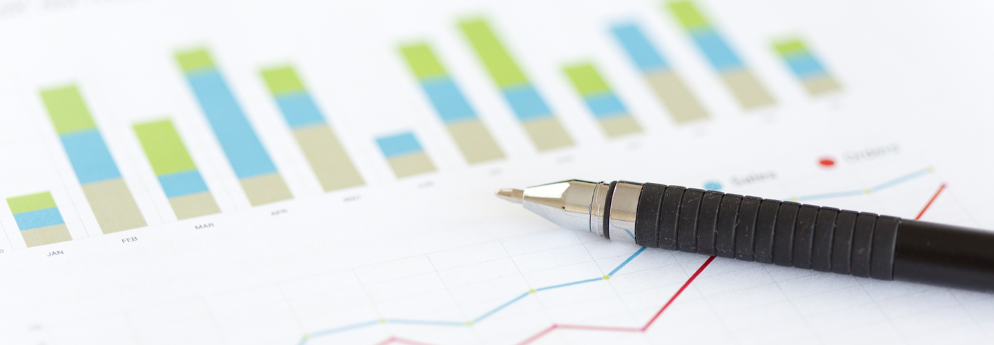 Close-up of a pen laying on top of printed charts.