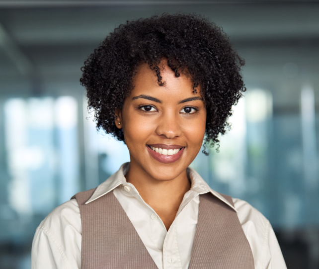 A portrait of a young Black woman with curly hair, wearing a light-colored collared shirt and a brow 