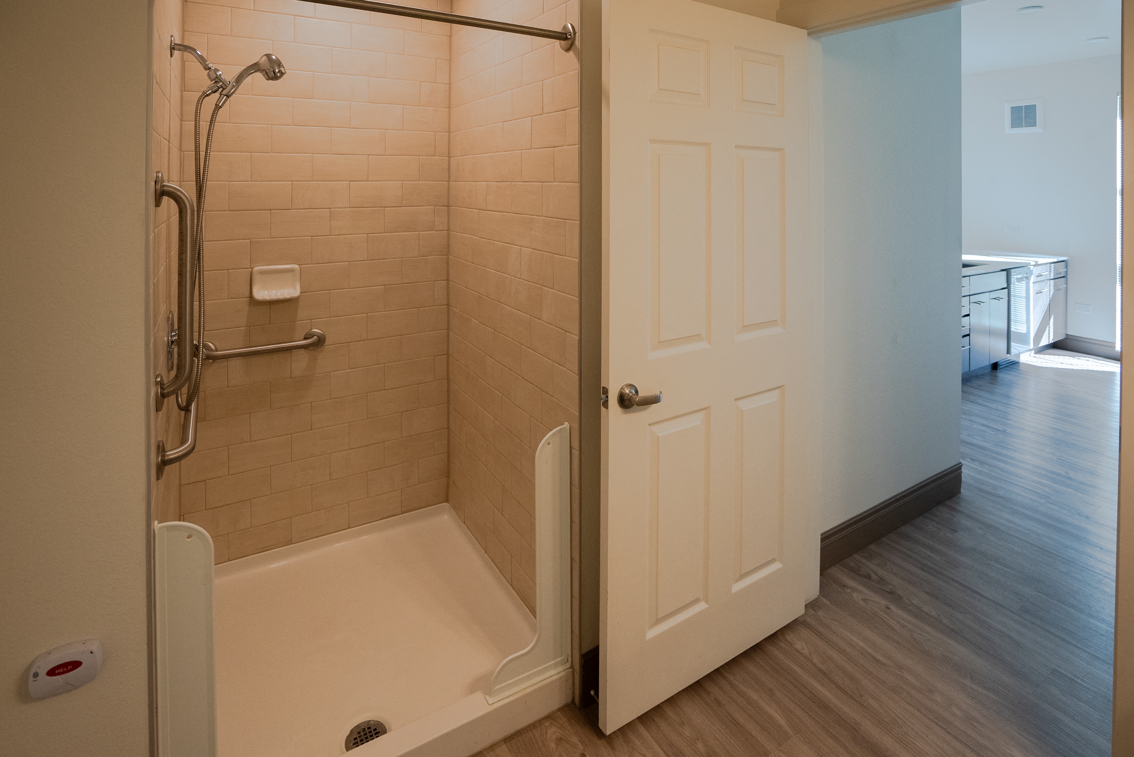 A bathroom with a walk in shower and a white door.