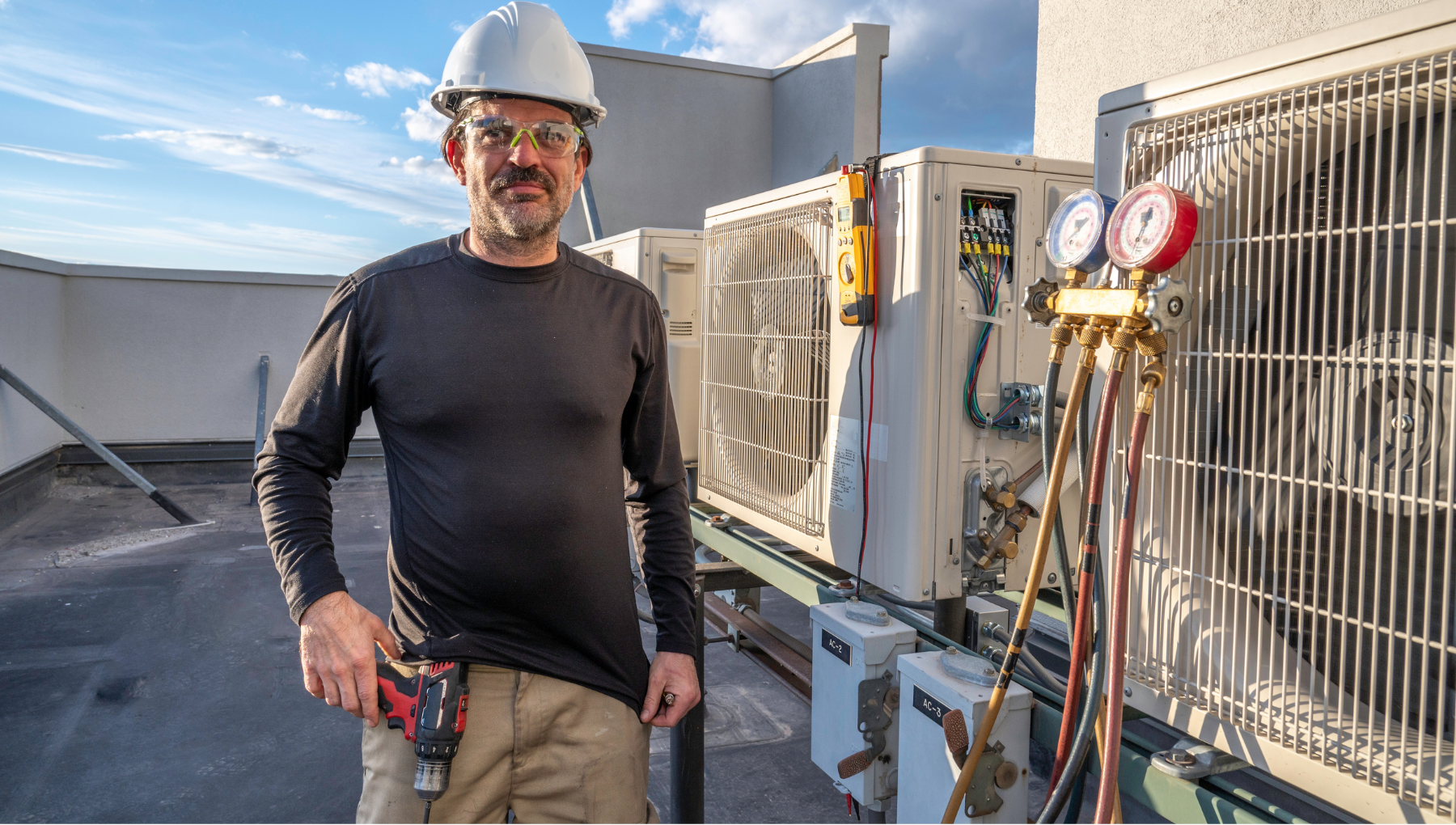 Certified HVAC technician performing maintenance on a commercial rooftop air conditioning unit. Equipped with professional tools, including pressure gauges and a power drill, ensuring optimal system performance. MAX Comfort HVAC provides expert HVAC installation, repair, and maintenance services in Allentown, PA, delivering high-quality solutions for residential and commercial buildings.