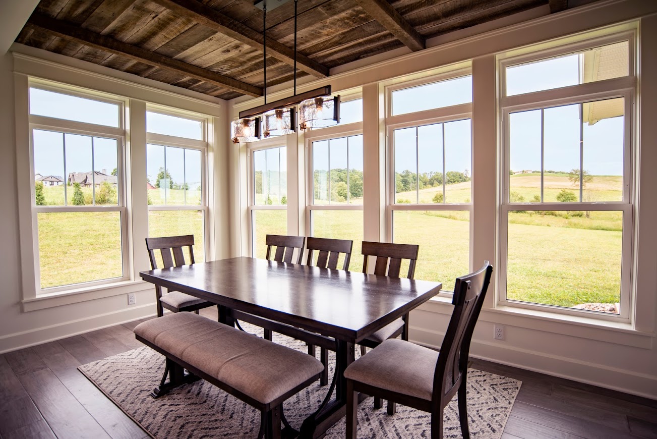 The EcoTek 3200 Series Double-Hung Windows with internal grids bring elegance and natural light to this dining room, enhancing its warm and inviting atmosphere. The clean lines and classic design of the windows perfectly complement the rustic elements of the space, creating a beautiful balance of style and function.