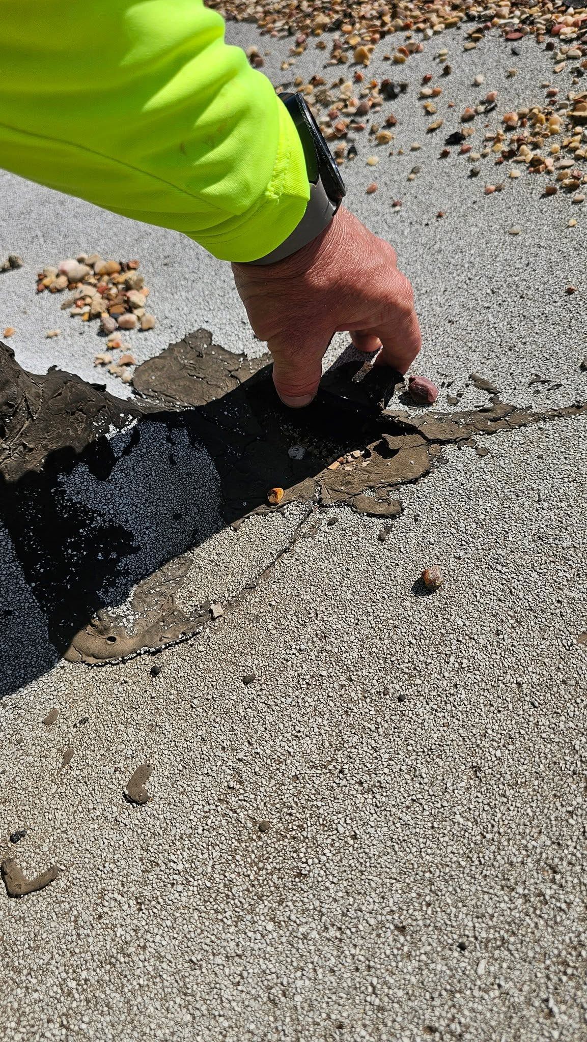 Technician examining deteriorated commercial roofing membrane to identify cracks, seam failure, and  