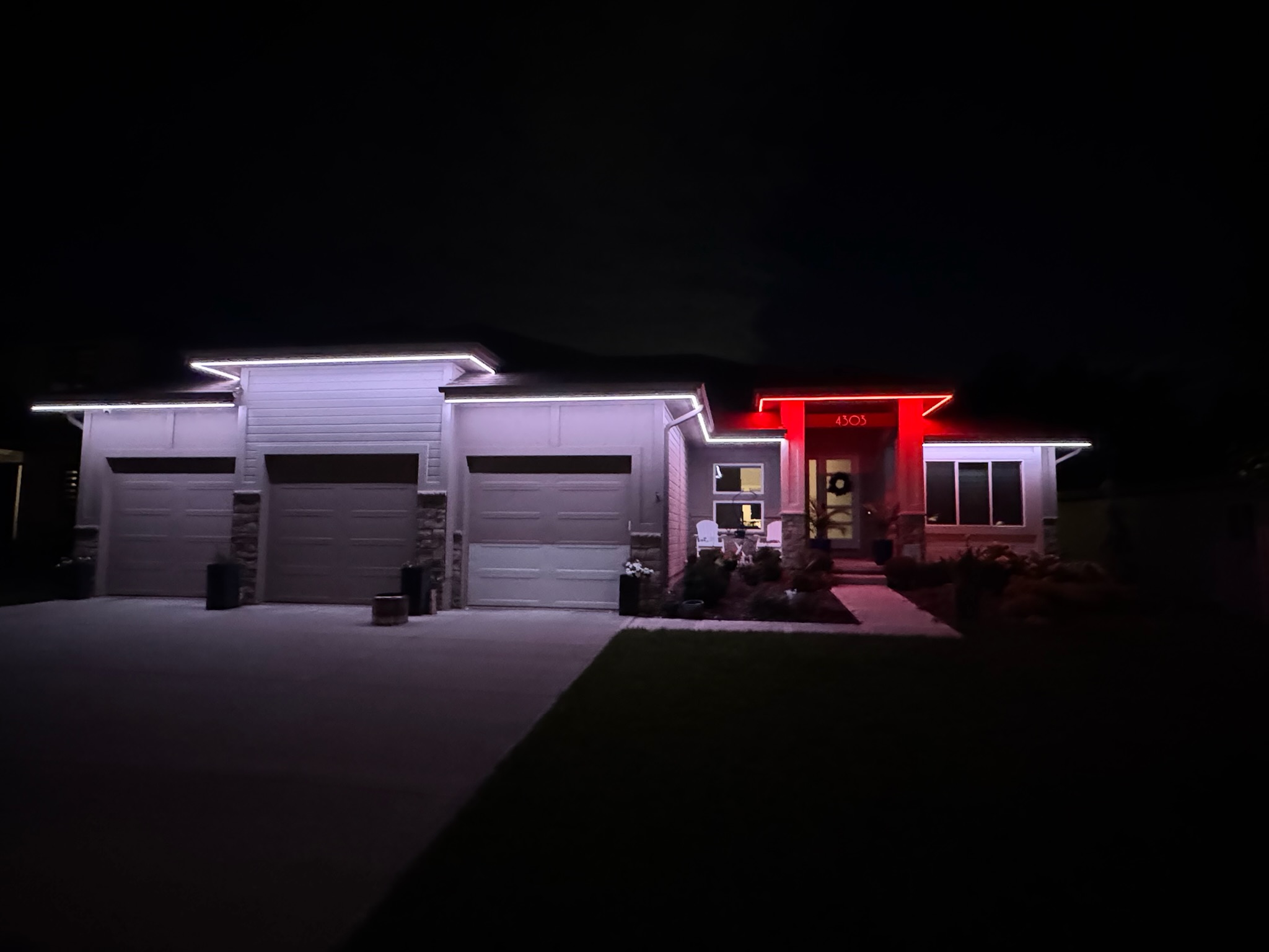 Multi-color outdoor lighting installation creating a custom nighttime look across the home&rsquo;s exterior.