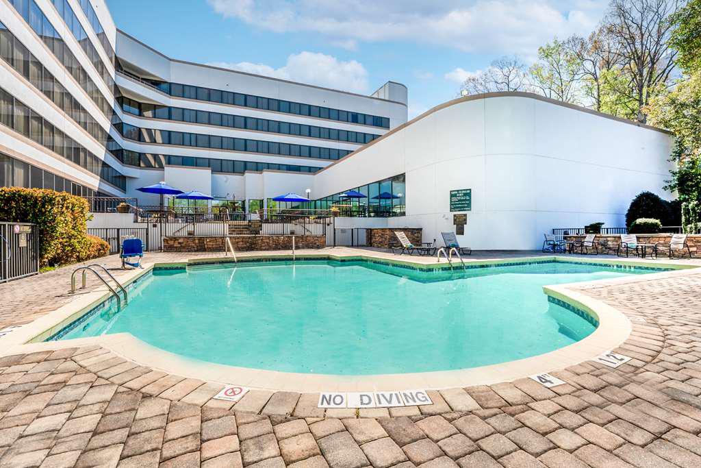 Seasonal outdoor swimming pool at DoubleTree South Charlotte Tyvola with umbrellas and hotel building