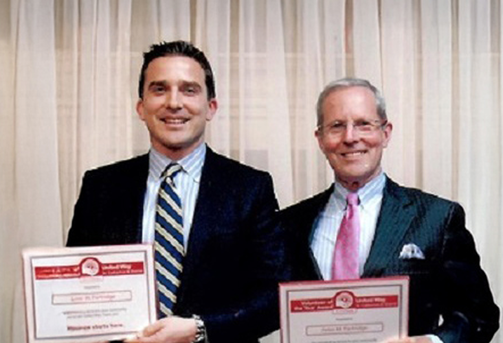 Peter Partridge and his dad smiling and holding awards from United Way Niagara.