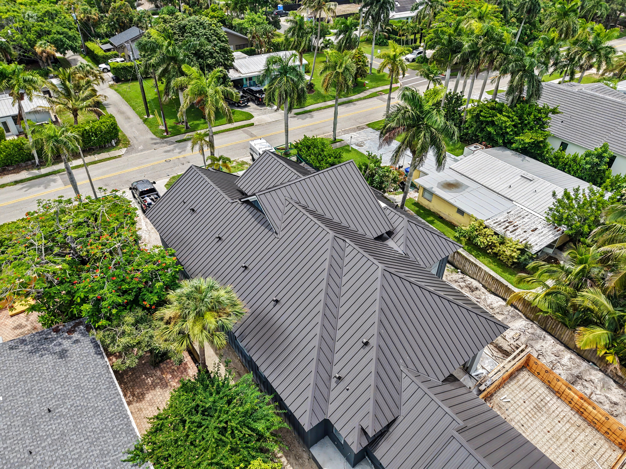 Angled aerial view of a newly constructed home featuring a dark standing seam metal roof with multip 