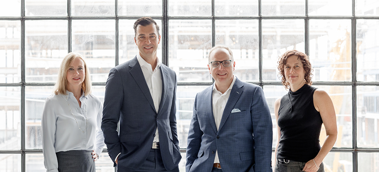 The Barasch - Wellwood team standing side by side in front of a large window.