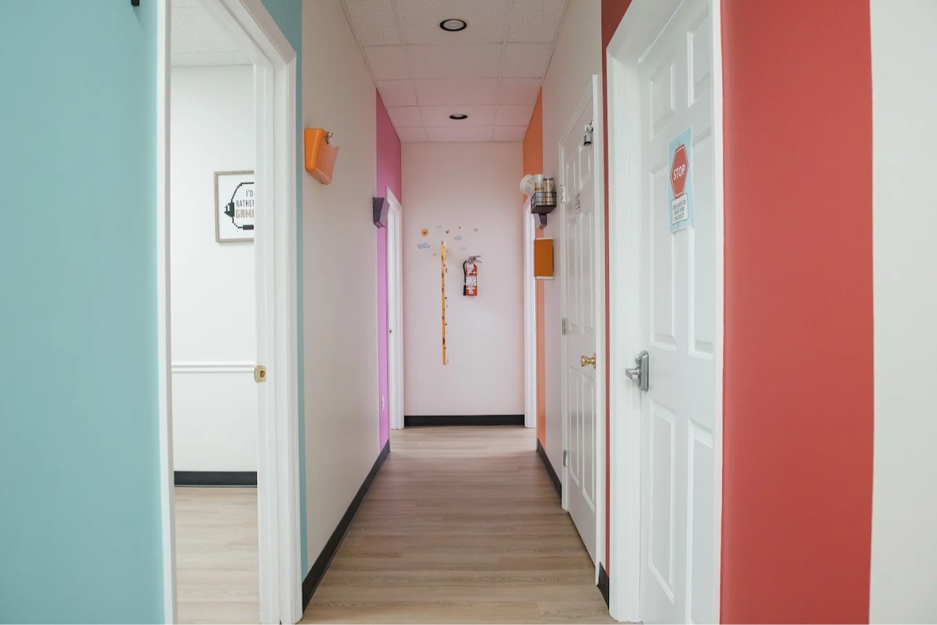 Bright pediatric clinic hallway at A+ Pediatrics in Irvine, Kentucky, with colorful walls and exam room doors.