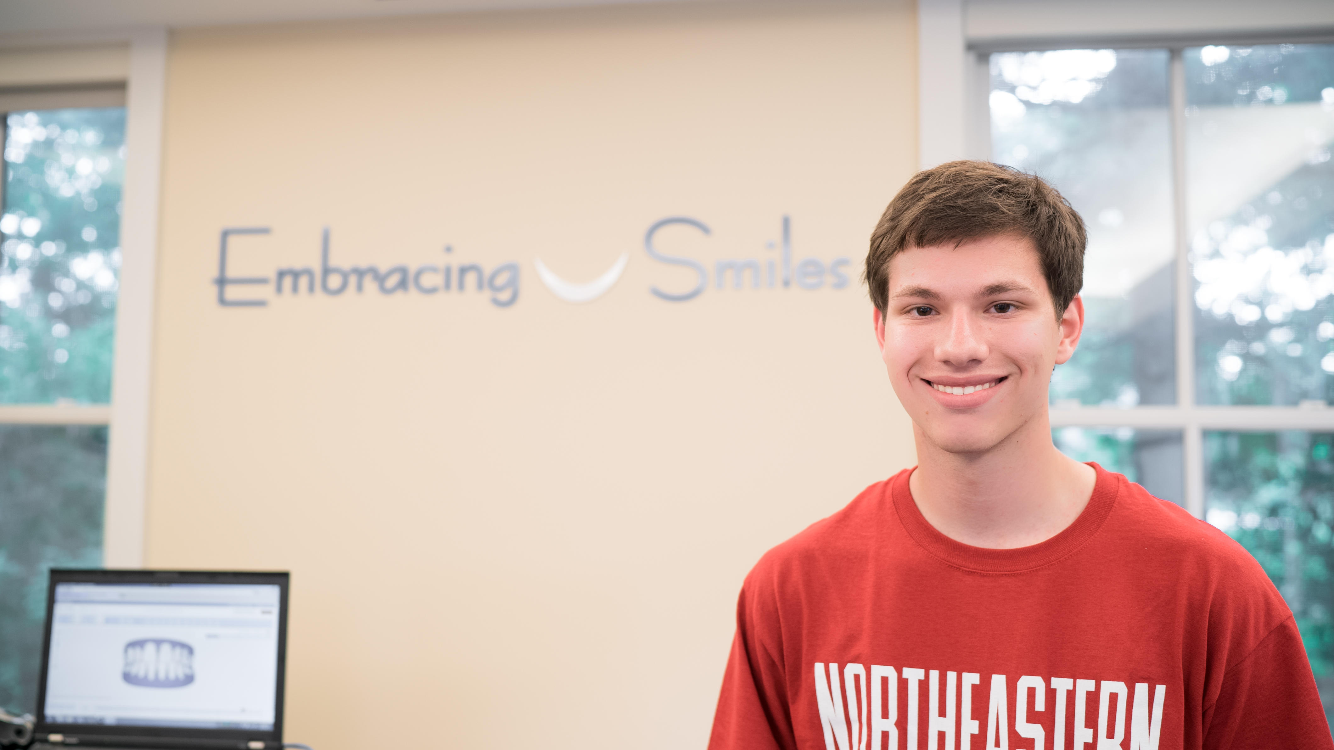 Teen boy who had invisalign treatment smiling at orthodontics office in new york