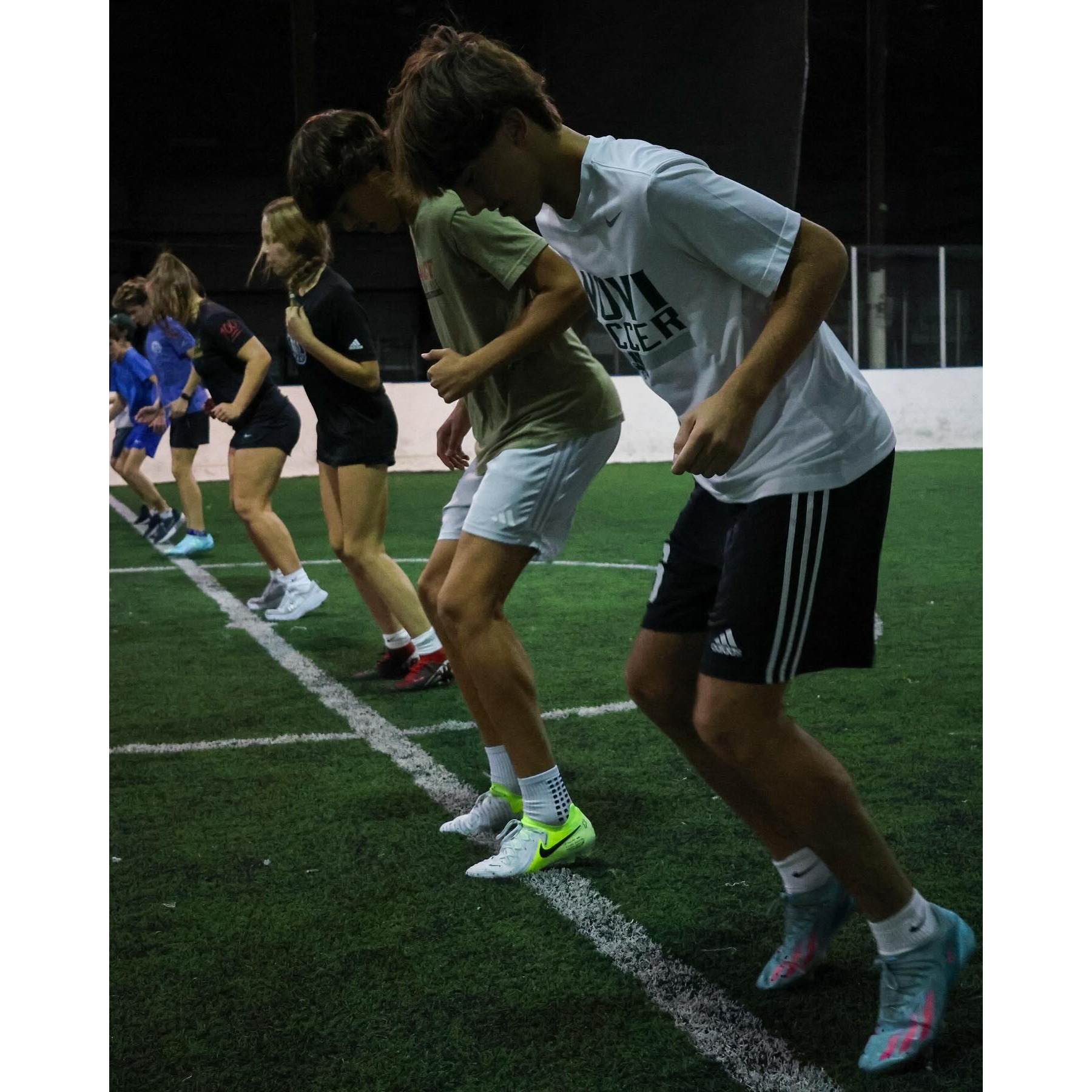 Group of athletes performing footwork and agility drills on turf at Impact Sports Performance