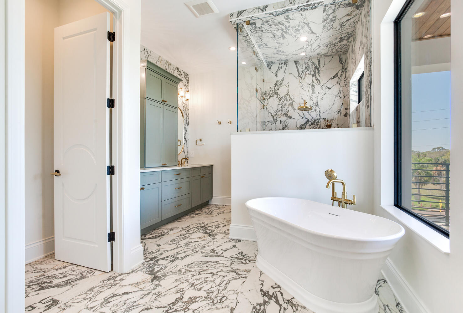 Luxury bathroom with a freestanding soaking tub, walk-in shower, marble-look tile, wood accents, and large windows for natural light.