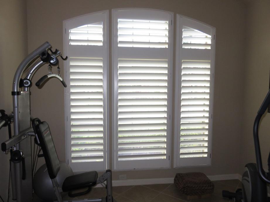 Get the privacy you need in your home gym. This Katy, TX home has beautiful arched windows that look perfect with Hidden Tilt Plantation Shutters by Budget Blinds of Katy & Sugar Land.