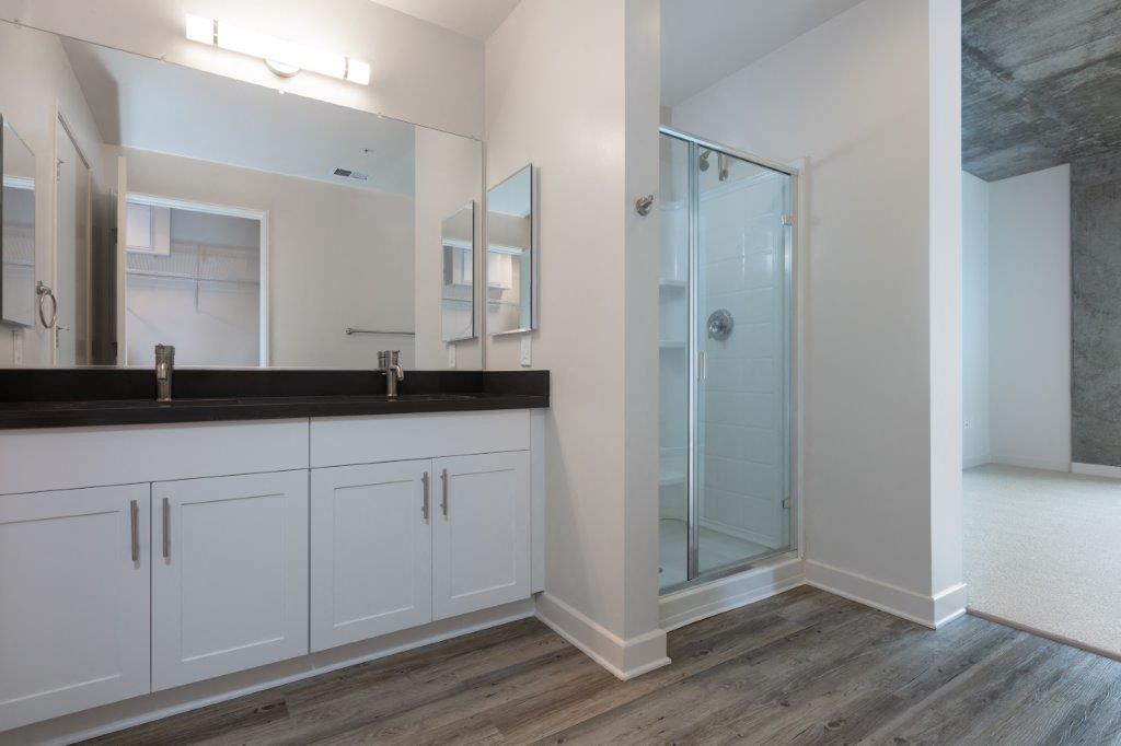 Oakland CA Apartments-Aqua Via Apartments Bathroom With Glass Door Shower And Double Sink Vanity And Vinyl Plank Flooring