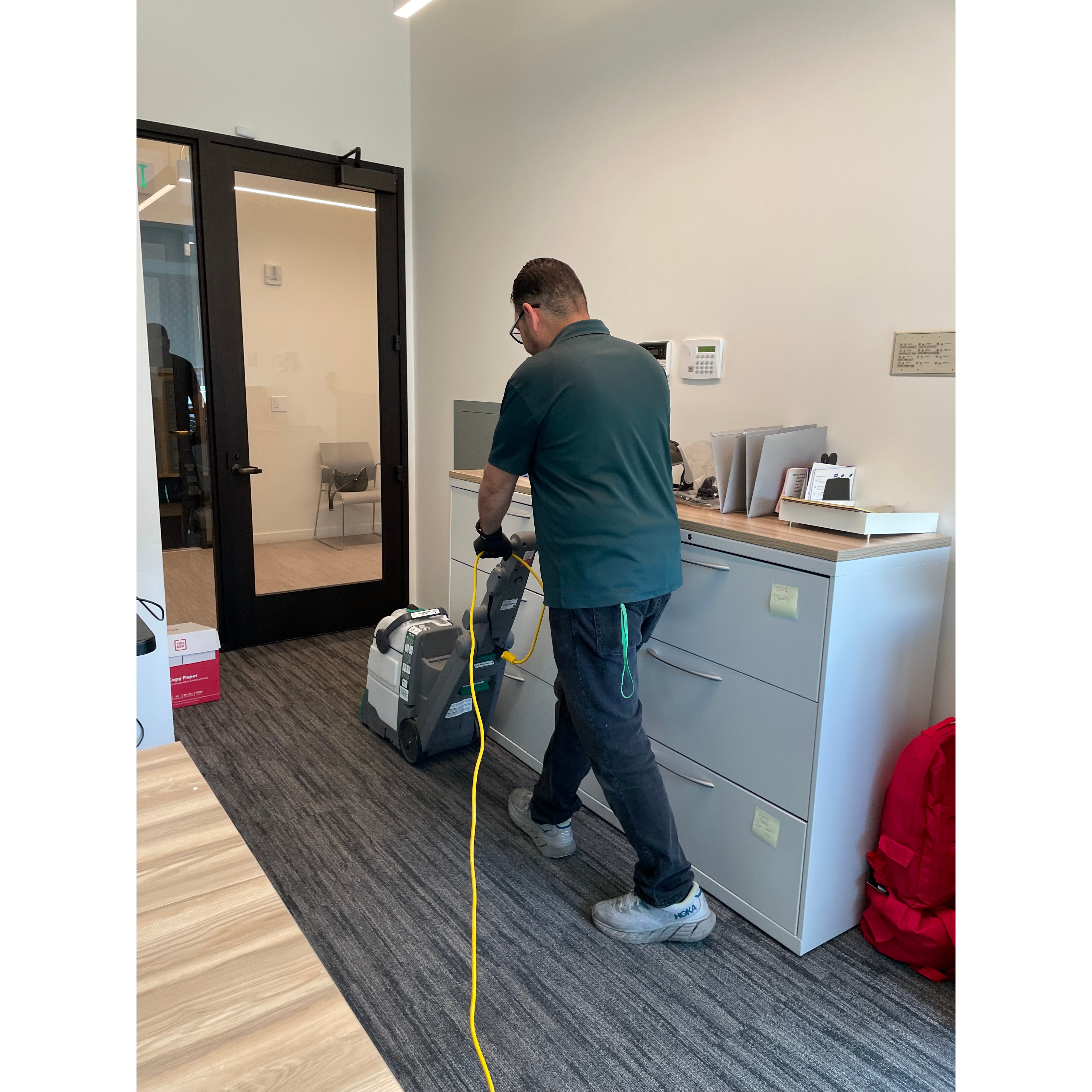 A Star's Janitorial Services team member vacuuming carpet in an office reception area as part of routine commercial janitorial service.