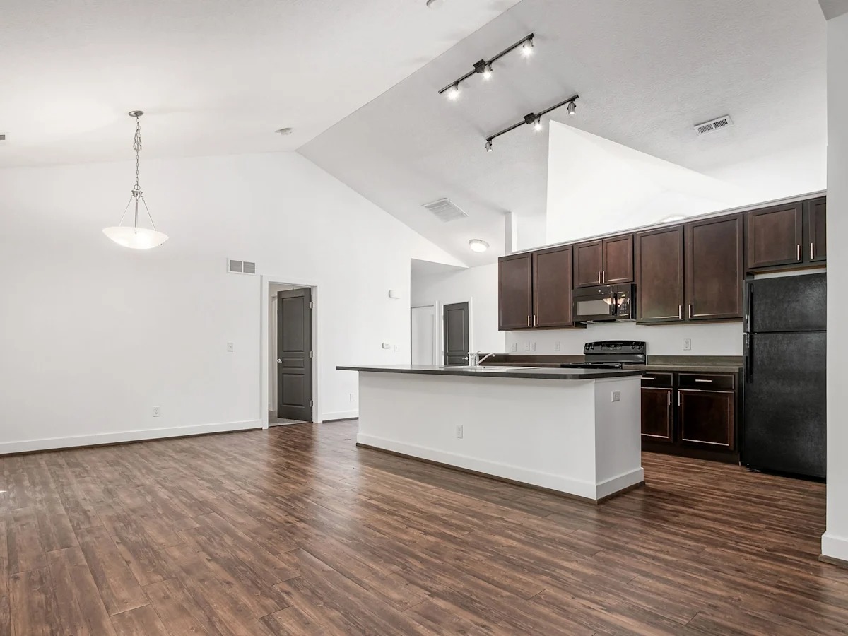 A kitchen with a white island and dark wood floors.