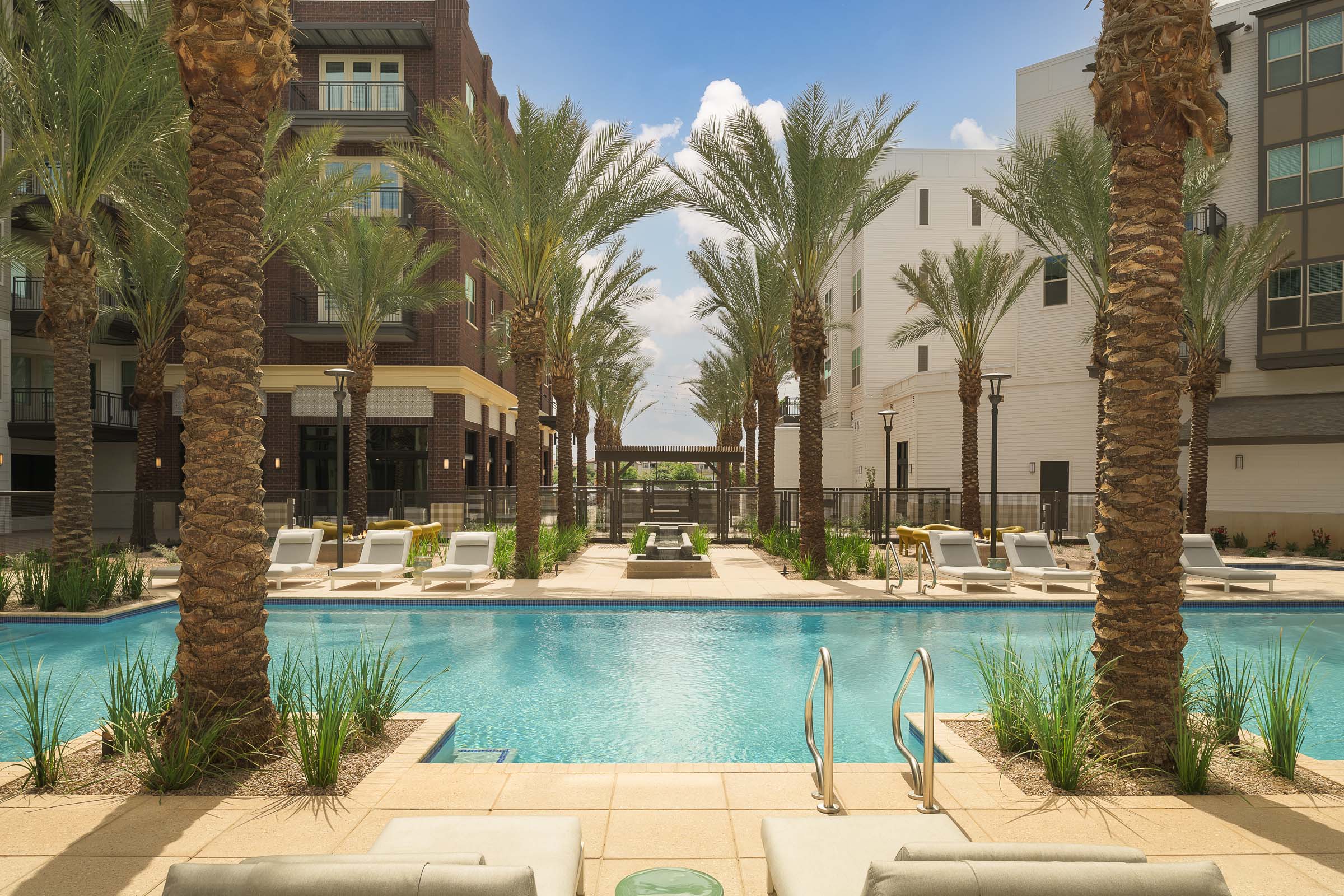 Oasis-style pool lined with palm trees and seating at Camden Gilbert apartment homes in Gilbert, AZ