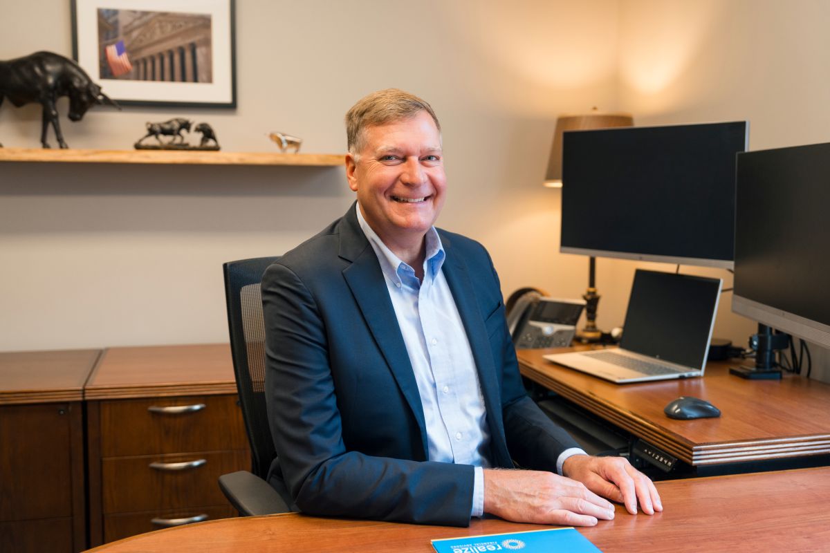 A professional portrait of a financial advisor seated at his desk inside the Realize Financial Advis 