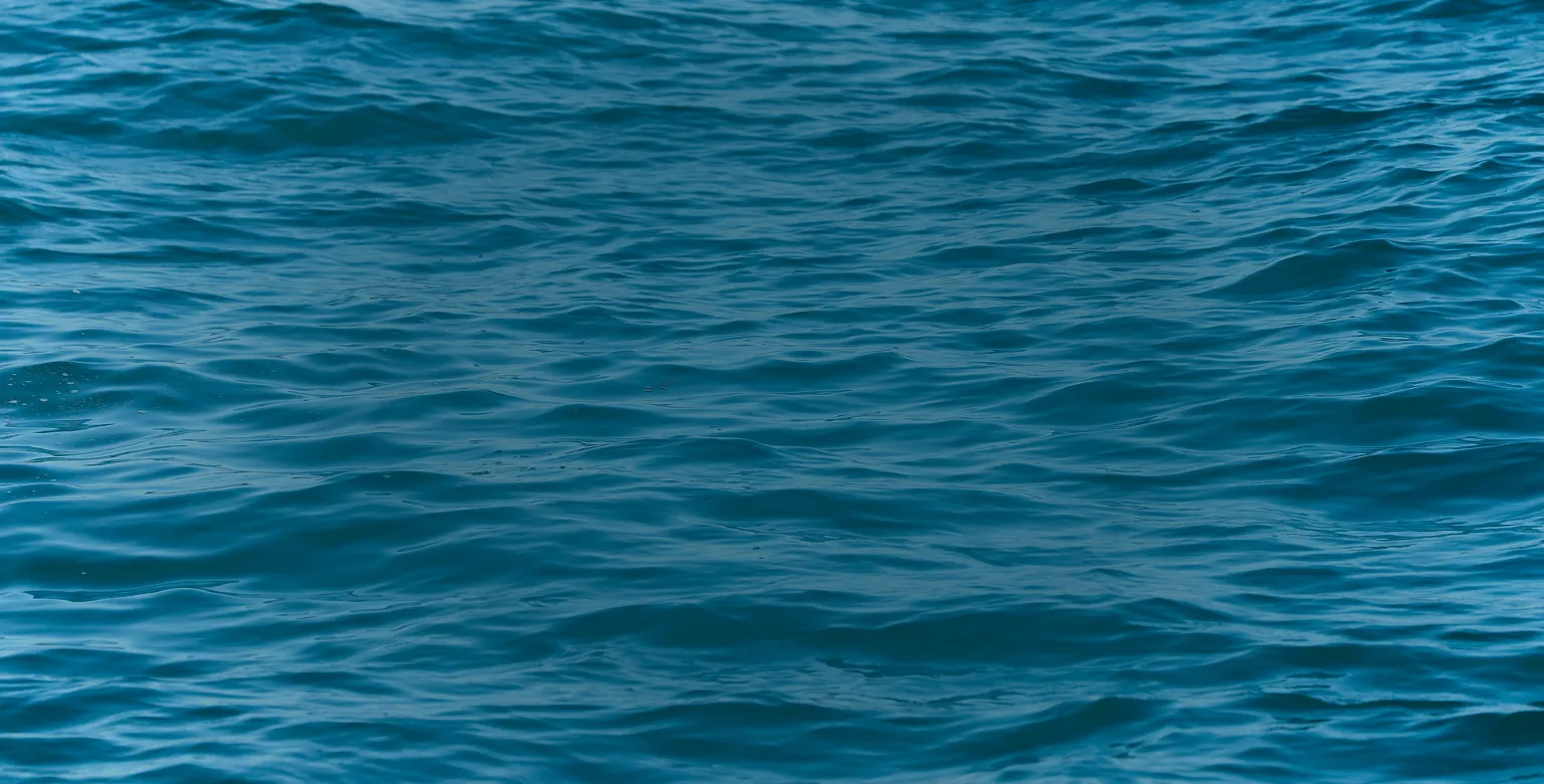 A textured surface of rippling blue ocean water.