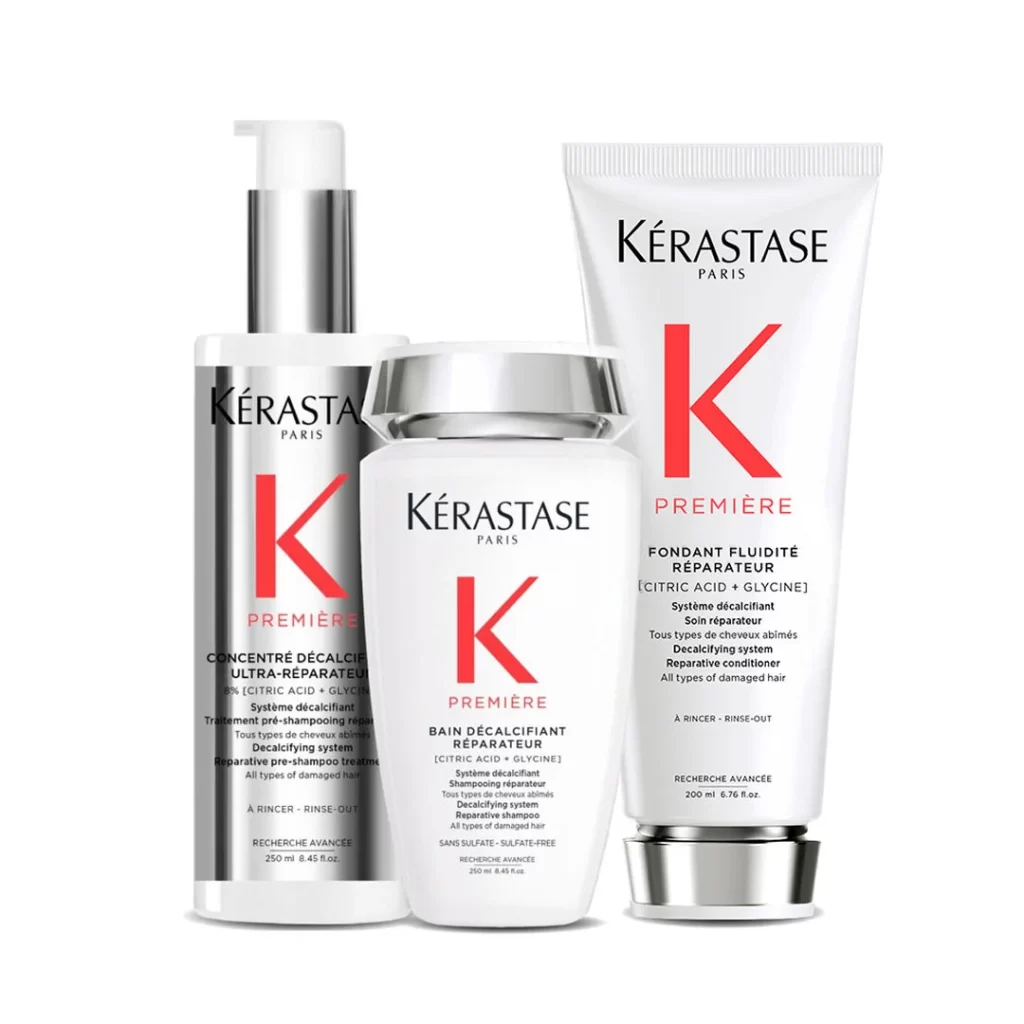 Three Kérastase Première hair products are displayed against a white background. The products include a concentrated repairing serum, a repairing shampoo, and a repairing conditioner. Each product features the Kérastase logo and the "Première" line branding in red and white.
