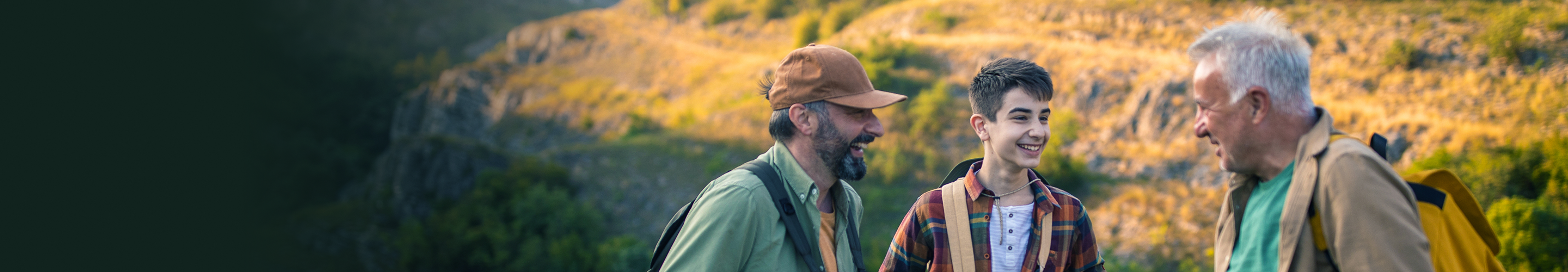 A grandfather, son, and grandson laughing together during a hike.