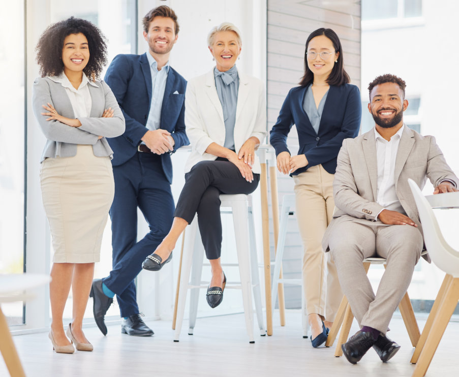 A diverse group of five professionals, three women and two men, are posing together in a well-lit of 