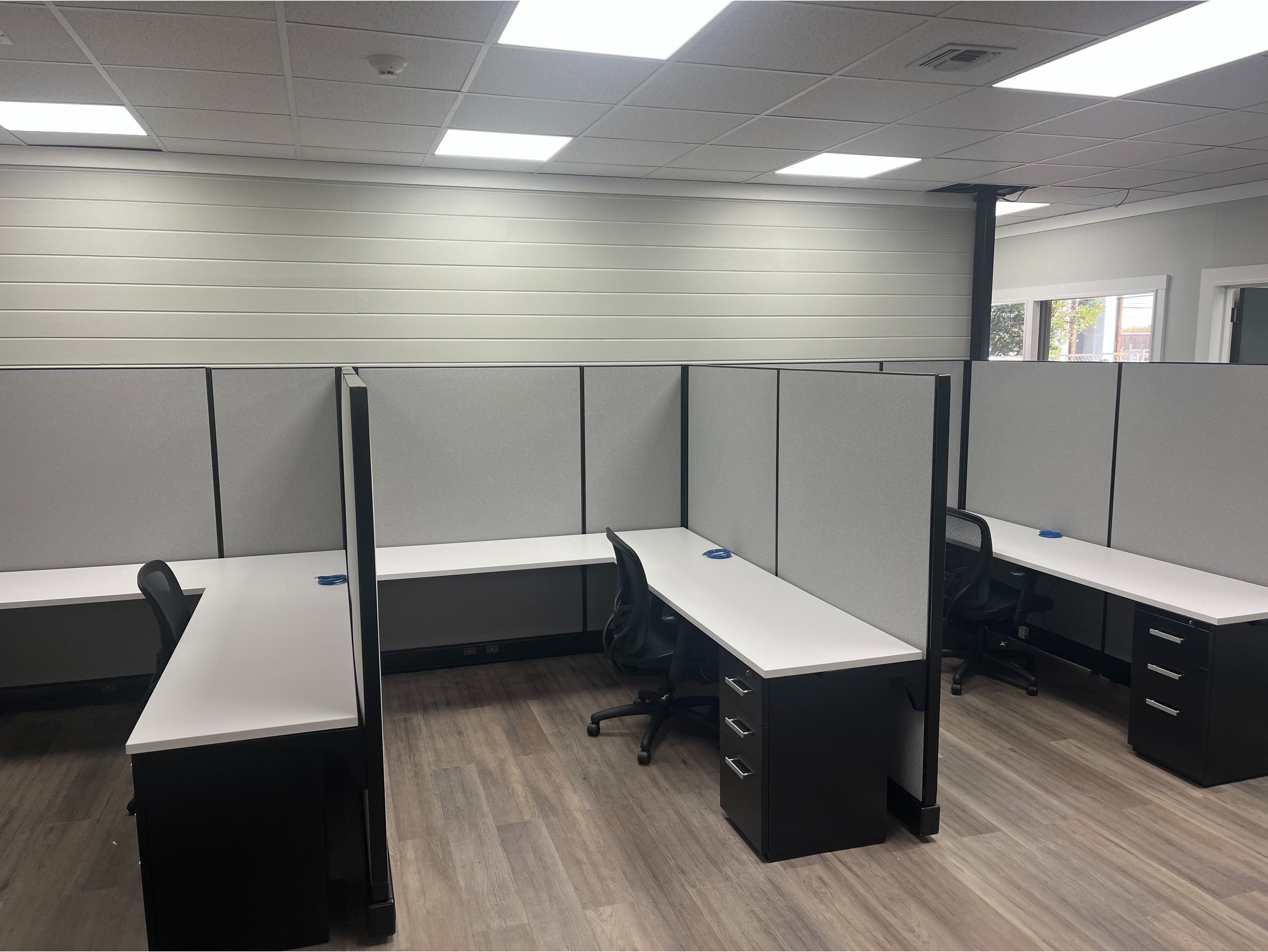 Row of Modern Workstations:

Streamlined office cubicles with tall gray fabric dividers and dark wood laminate desks, ideal for high-density office layouts.