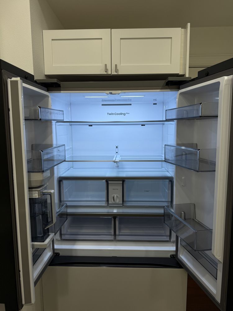 An open, empty refrigerator with clean shelves, drawers, and door compartments, illuminated inside, showcasing a spotless interior and organized storage space after thorough cleaning in a modern kitchen setting.