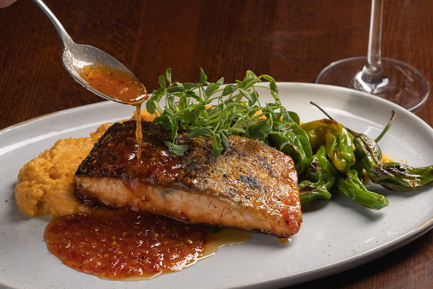 Crispy Skin Sweet Chili Salmon with the sauce being spooned on at The Independent in the Theatre District.