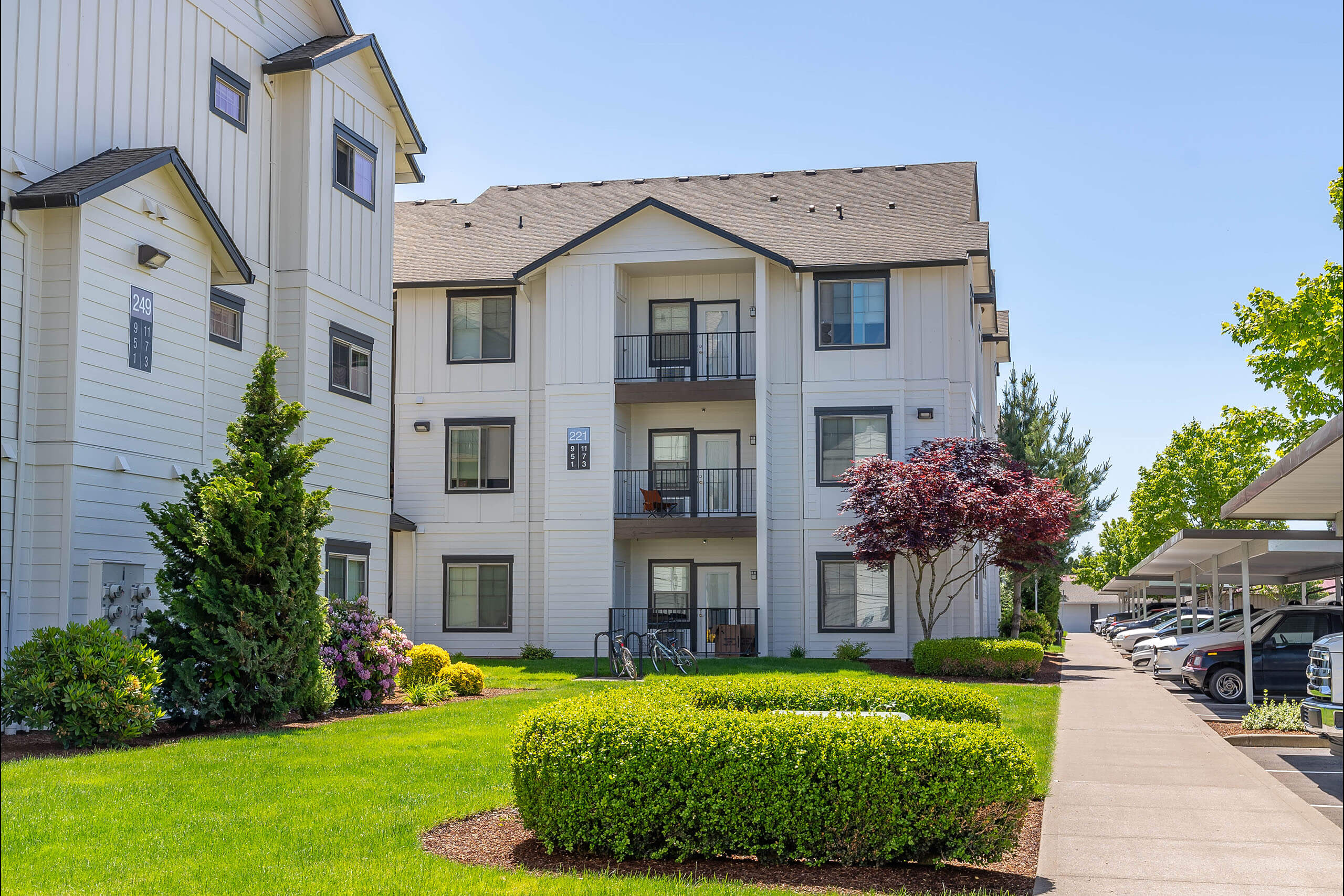 A white apartment building with a green lawn in front.