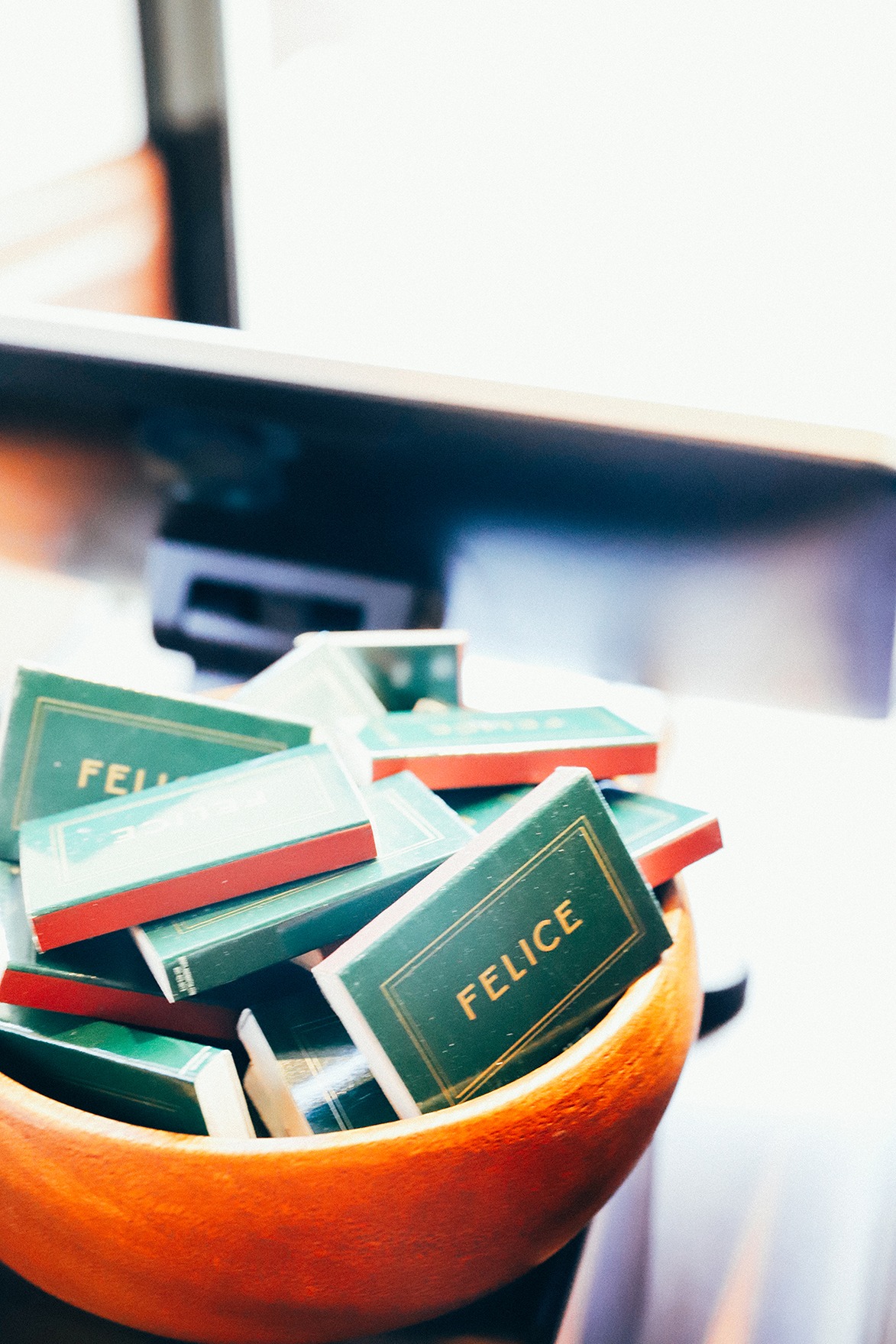 A wooden bowl filled with forest green and gold embossed "Felice" matchboxes, a signature takeaway for guests at the restaurant.