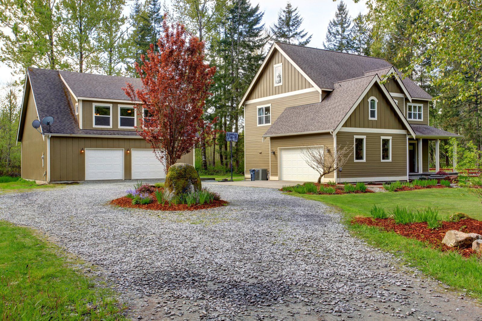 Freshly installed gravel driveway leading to a residential property, surrounded by landscaping and trees. Proper grading and gravel placement ensure durability, drainage, and improved curb appeal for homeowners seeking reliable driveway installation services.